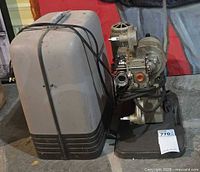 Projector next to carrying case, cords visible