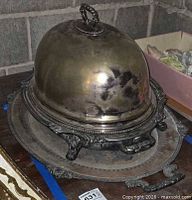 Meat dome on warming base placed on serving tray, showing tarnish and ornate details