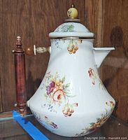 Left-side view showing floral pattern, wooden handle and spout