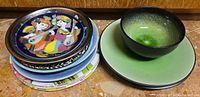 Stacked assortment of decorative plates and separate green crackle-glaze dinnerware