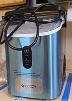Front view of Ecozy stainless steel ice maker showing control panel and logo