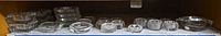 Shelf with multiple Heisey crystal ashtrays, coasters and small dishes