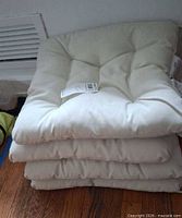 Stack of four off-white tufted seat cushions