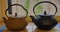Two Kotobuki cast iron teapots side by side