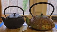Both cast iron teapots side by side on windowsill