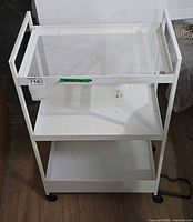 Full view of white three-shelf metal cart on casters