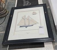 Framed print featuring schooner with sails and small inset sketch, black frame