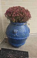 Front view of blue speckled ceramic planter against brick wall