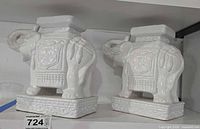 Both white ceramic elephant stands on shelf