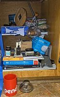 Cabinet shelf with Echo Dot box, inkwell components, paper reams, ink bottle, pencil holder, digital scale, stapler
