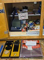 Cabinet view showing DYMO kit, Staples folders, assorted stationery