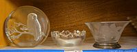Three glass items side by side: owl paperweight, vide-poche bowl, etched bowl