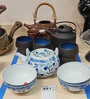 Full lot showing four teapots, cups and bowls