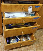 Four drawers open showing linens, stretch-tite wrap boxes and utensil drawer