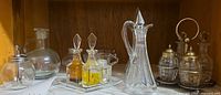 Overview of all glassware including pitchers, decanters, rectangular cruet set, small mustard pot and silverplate cruet set