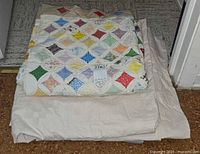three folded quilts stacked, top shows patchwork diamond design