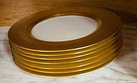 stack of seven gold rimmed plates showing rim design