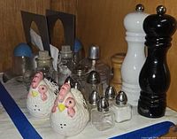 Group shot showing Michael Graves napkin holder, ceramic hens, glass shakers, and three grinders