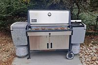 Front view of Weber Summit Gold grill showing burners, side cabinets and propane tanks