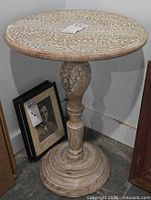 Full view of round carved wood table with pedestal and base