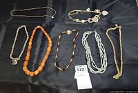 All seven necklaces laid out on black cloth