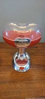 Front view of Jelly Belly candy dispenser showing clear bean-shaped hopper, red column and chrome base