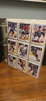 Open binder displaying nine pocket pages with Upper Deck hockey cards