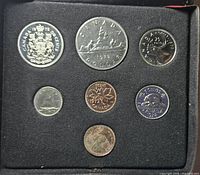 Open case showing seven coins in black flocked insert