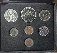 Open display case showing all seven 1975 coins seated in black insert