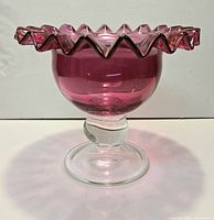 Side view showing cranberry bowl, ruffled rim, clear pedestal and foot