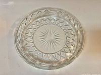 top view of clear pressed glass plate showing starburst center and lattice border
