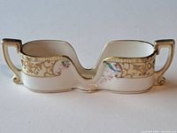 front view of double-well porcelain spoon caddy showing gold gilt and floral design