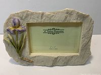 Front view of stone-look resin frame with iris detail and Kubang Corporation insert card