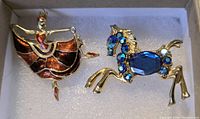 Both brooches in box: dancer with enamel skirt and horse with blue stones