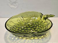 Olive green pressed glass leaf-shaped bowl showing overall form, handle, and raised pattern