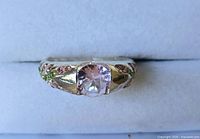 Front view of silver-tone ring displaying light pink center stone and accent stones