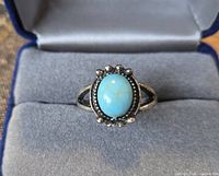 Front view of silver-tone ring with oval turquoise cabochon and beaded halo