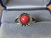 Ring with red cabochon and beaded halo in open box