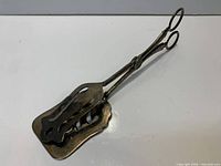 Full view of silver plated scissor serving tongs closed