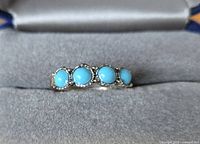 ring in presentation box showcasing four turquoise cabochons and silver-tone setting