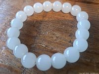 Full view of white jade beaded bracelet on wooden surface
