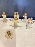Six Willow Tree figurines and plaque arranged on table