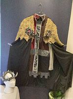 Full costume hanging showing cloak, tunic and helmet