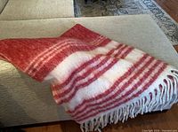 Full view of red and cream striped throw draped over furniture