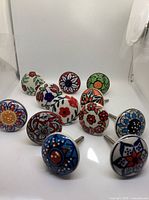 Group view of all 12 multicolor floral ceramic knobs standing on bolts