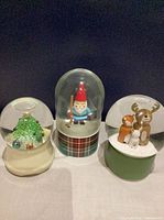 Front view of all three snow globes showing different scenes and bases