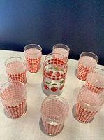 Eight small gingham glasses circled around one cherry tumbler