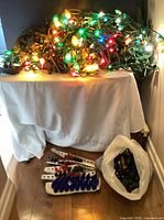Powered C9 and C7 light strands lit on table alongside loose bulbs and bag