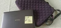 Closed Asus laptop next to purple quilted sleeve