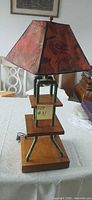 Front view of handmade lamp showing wood tiers, green pipes, red marbled shade